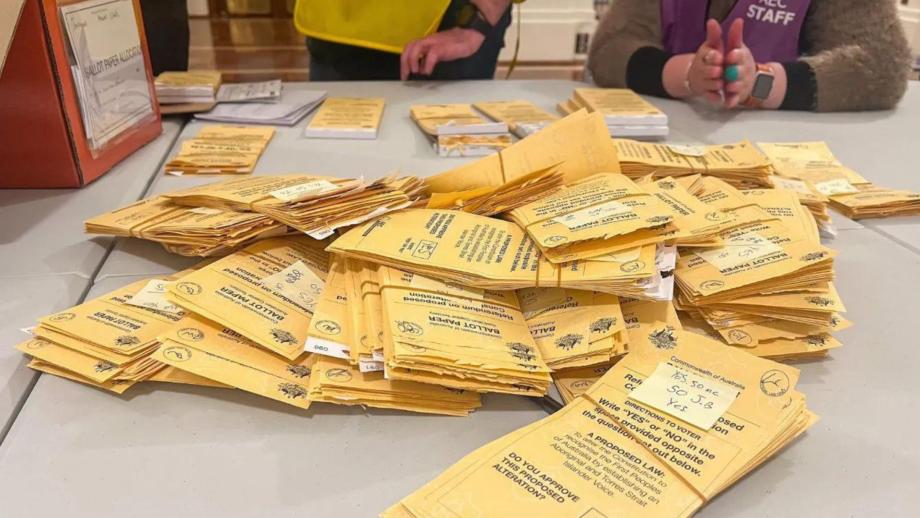 A stack of yellow ballot papers sitting on a white desk.