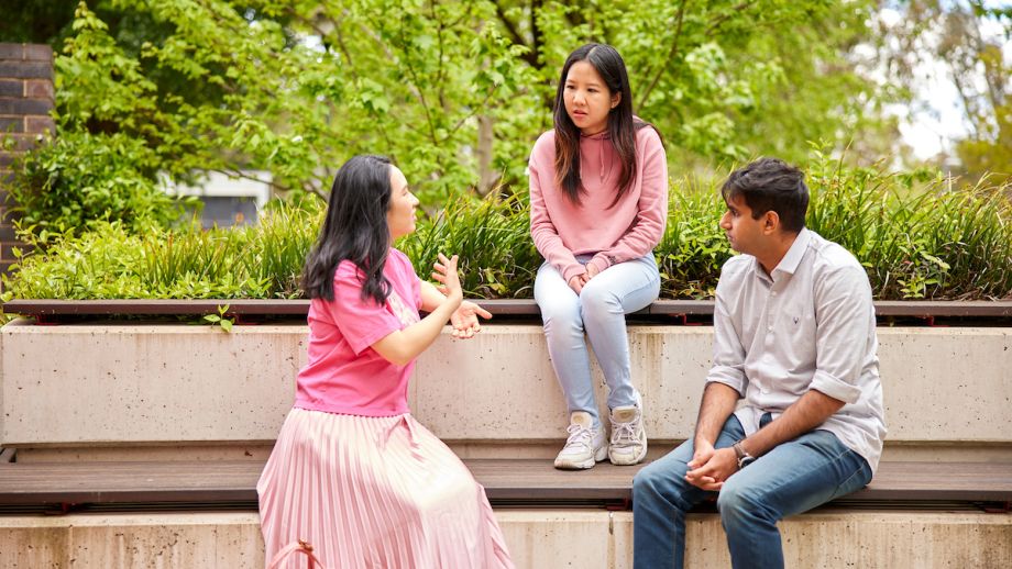 Three ANU community members talking outside on campus.