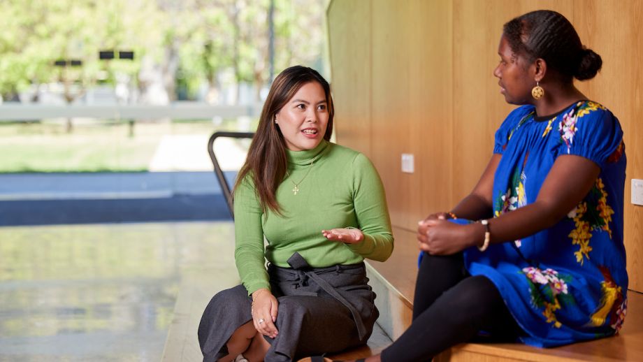 Two ANU community members sitting and talking inside a sunlit campus building.
