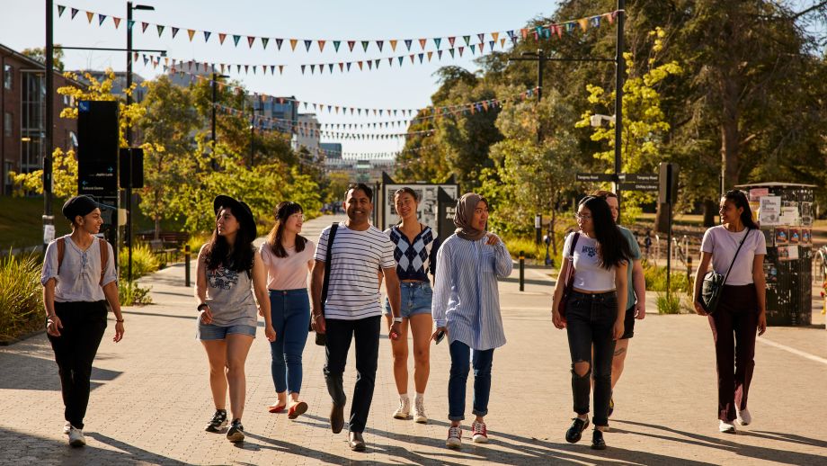 Diverse group of students walking and smiling on campus.