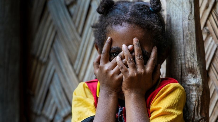Photo of a young girl whose family members have been accused of sorcery hides her face in the settlements outside Goroka, Papua New Guinea, by Adam Browne.