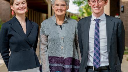 3 people stand side-by-side smiling. 