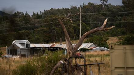 Powerlines across a cloudy sky and a converted shearing shed into a house in Canberra, ACT