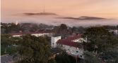 Aerial view of University House in Canberra with fog and Telstra tower in the background.